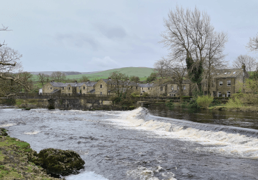 The river rushes powerfully over a weir and beneath a bridge.