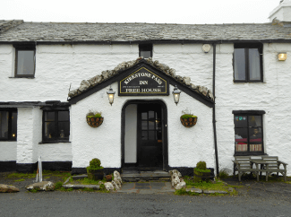 Entrance to the Kirkstone Pass Inn by Andrew Bowdon. The Kirkstone Pass Inn, a whitewashed building with lacquered black door and windowframes.