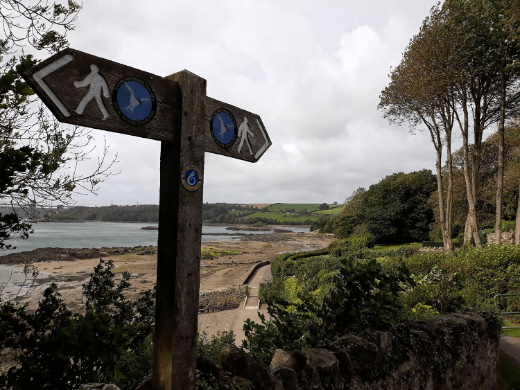 A signpost overlooking a sandy bay on the Anglesey Coast Path