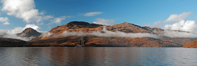 The mountains of Arrochar rise over a loch on the John Muir Way, a great first walking holiday.