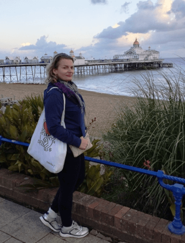 Gosia stands with views over the pier stretching out over the sea from the beach at Eastbourne.