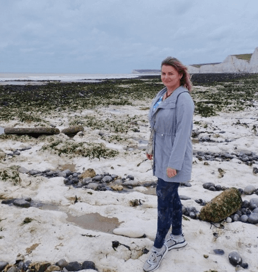 Gosia stands on the beach beneath the white cliffs of Seven Sisters.
