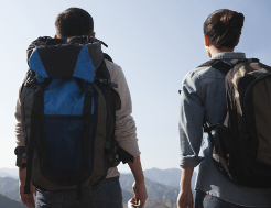 A pair of walkers pause to admire the scenery. They wear comfortable backpacks.