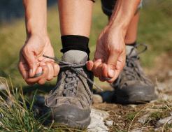 A beginner walker leans down to tie their walking boots that bit tighter.