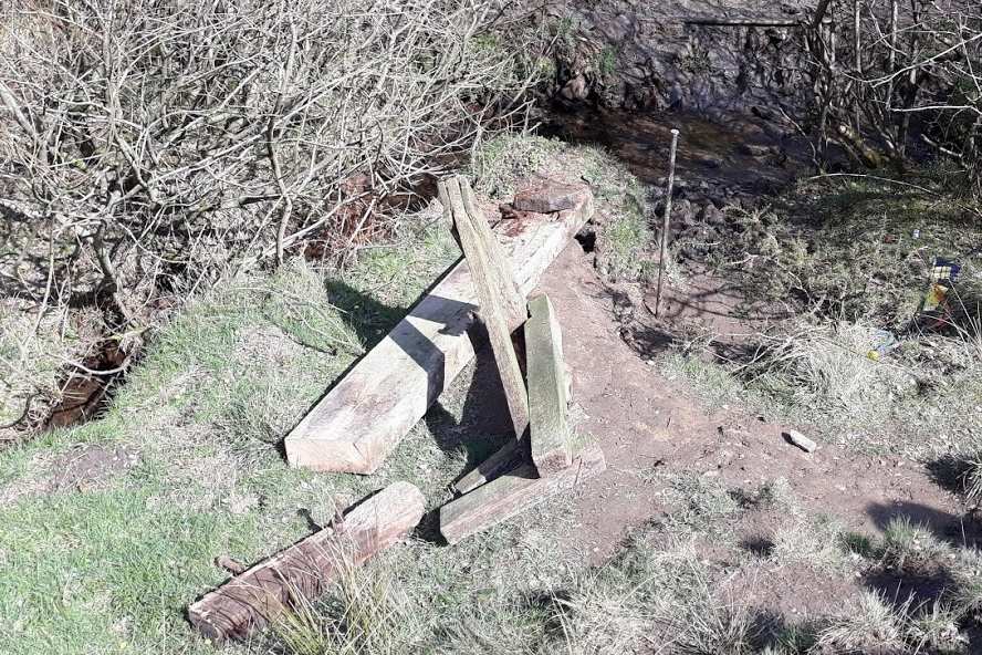 The bridge lies in pieces on the bank.