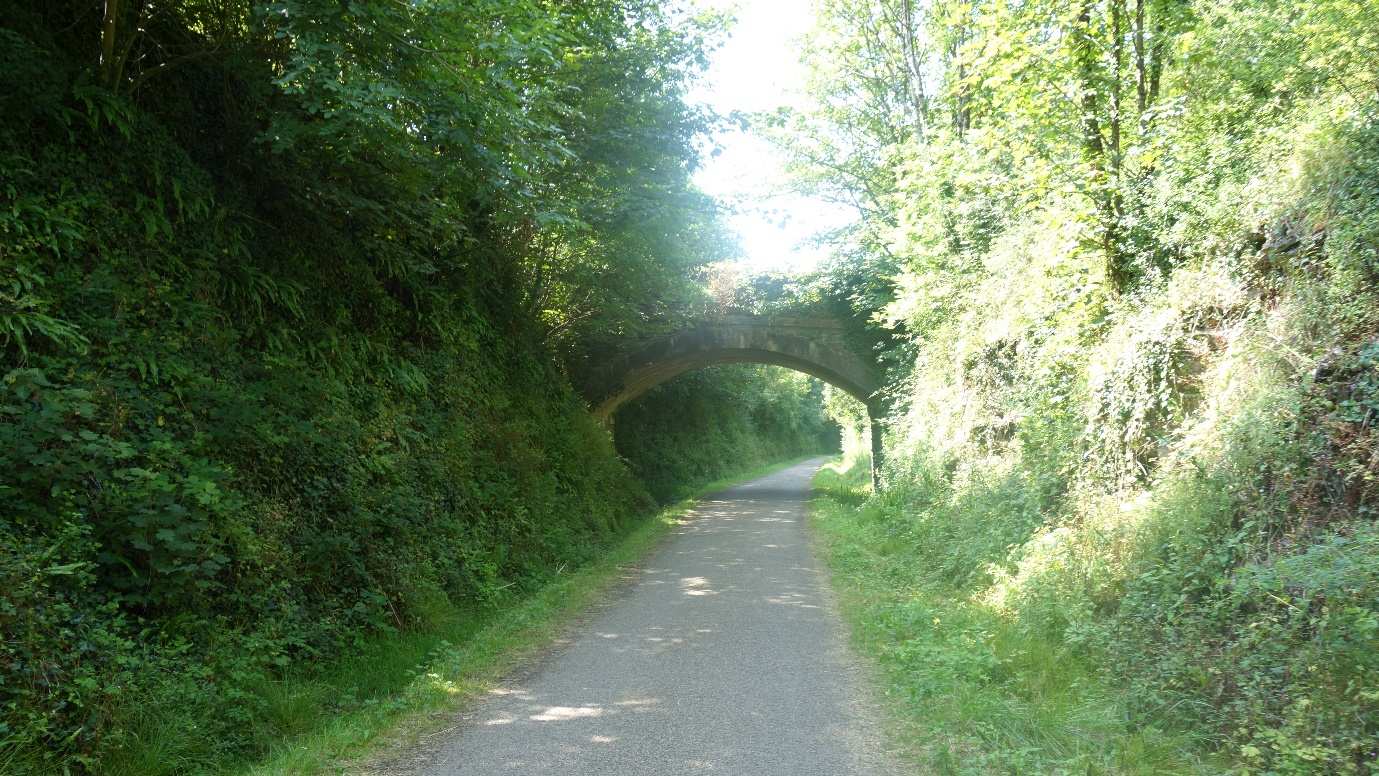 A stone bridge over a shade-dappled stretch of the Camel Trail