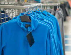 Fleeces hang from a railing in an outdoor shop, perfect for a beginner walker to wear as part of a layering system.