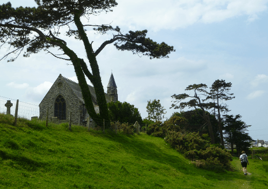 The Ceredigion Coast Path leads beneath a chapel and a pine tree on the walk into Borth