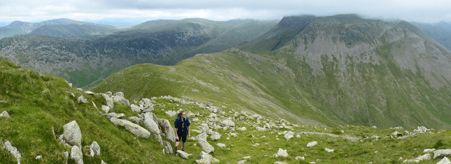 A male walker climbs high in the hills of the Lake District