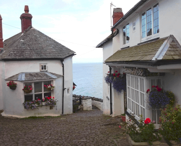 A cobbled street runs between two whitewashed cottages to the sea in Clovelly Village.