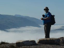 A photo of a walker standing on a fell above a temperature inversion in the UK.