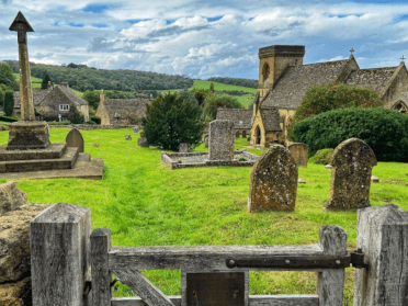 Views across a churchyard to a honey-stone church on a lesser-known trail in the Cotswolds.