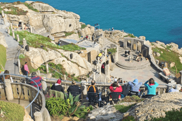 An audience crowds into the seats of the Minack Theatre to watch a play.