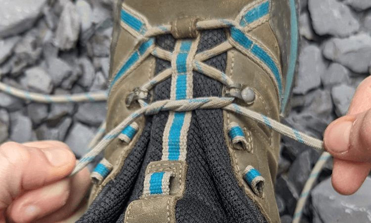 A double starting knot has been pulled tight in the laces of a pair of walking boots.