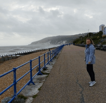 Gosia stands on the promenade at Eastbourne with views over the shoreline and sea.