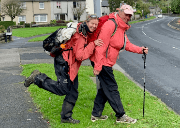 Two walkers out on a winter walk have fun posing with their winter layers: mainly waterproof coats and trousers.