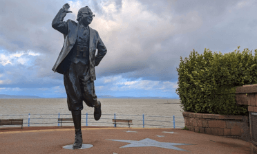 The famous Eric Morecambe statue stands with Morecambe Bay behind.