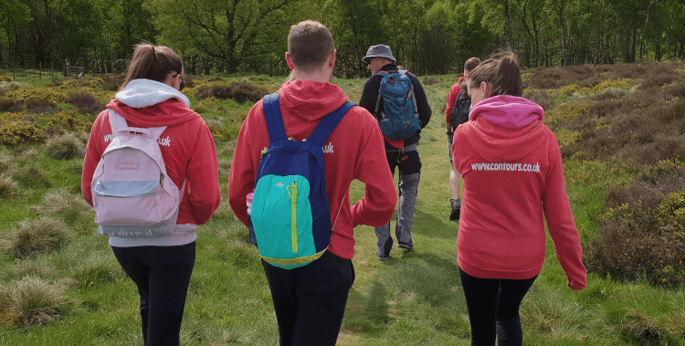 In their red Contours hoodies, staff head on a training walk into the countryside.