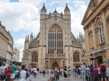 Bath Abbey surrounded by walkers and tourists exploring Bath town.