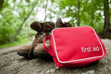 A walkers first aid kit sits unopened beside their boots.