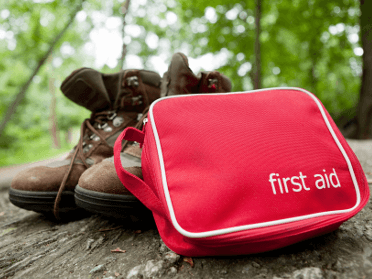 A first aid kit sits beside a hiker's boots.
