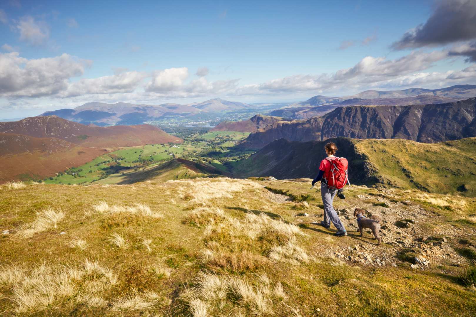 A walker follows a walking path above views over hills.