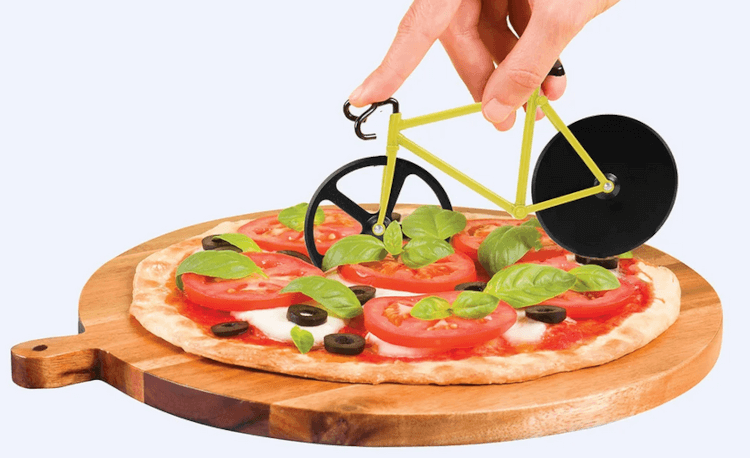 A pizza cutter in the shape of a bicycle is used to cut a slice of pizza.