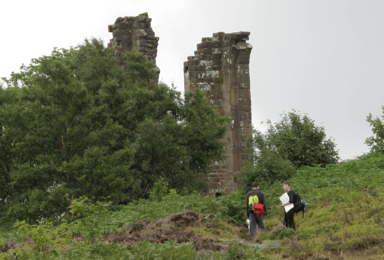 Yorke's Folly: two stone pillars towering over a pair of walkers on the Nidderdale Way.