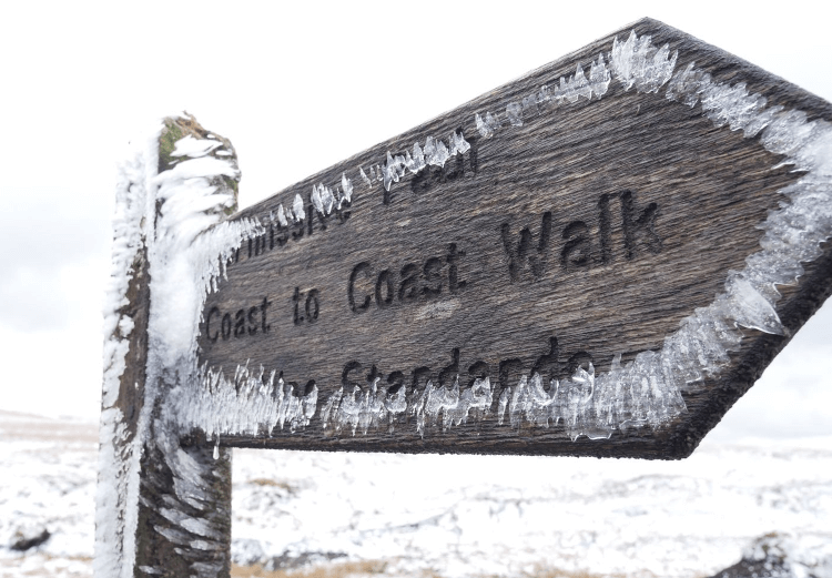 Frost encroaches on a wooden fingerpost pointing out the way of the Coast to Coast Walk.