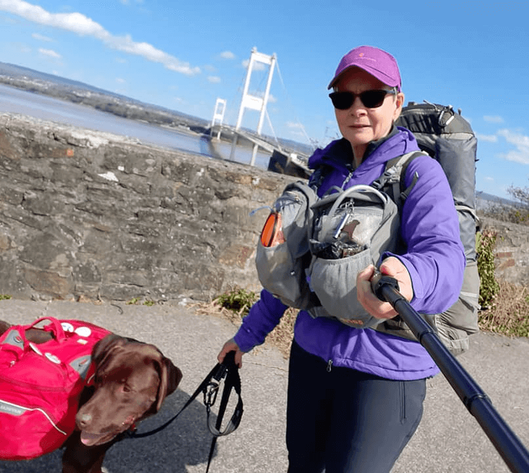 Yappy Hikers at the start of their walk with the estuary bridge behind, Gino in his red rucksack and Christine loaded up with bags.