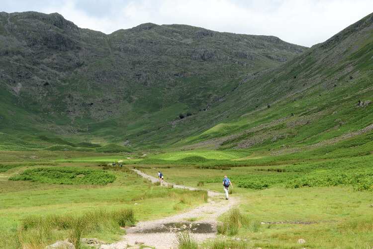 A path leads through grass toward the peaks at the head of Great Langdale on the Cumbria Way.