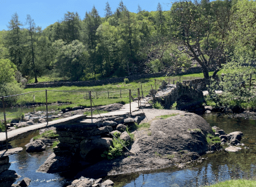 A stone bridge crosses a glittering river on the Lakeland Round walking tour, which could easily be connected to other Lake District trails to form an enormous grey-gapper tour.