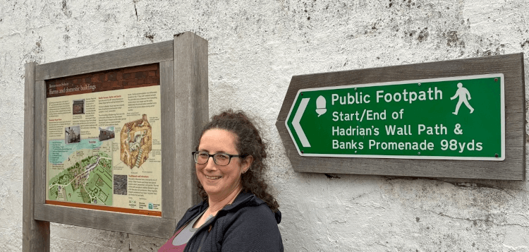 Posing beneath the sign pointing to the start of Hadrian's Wall Path in Bowness.