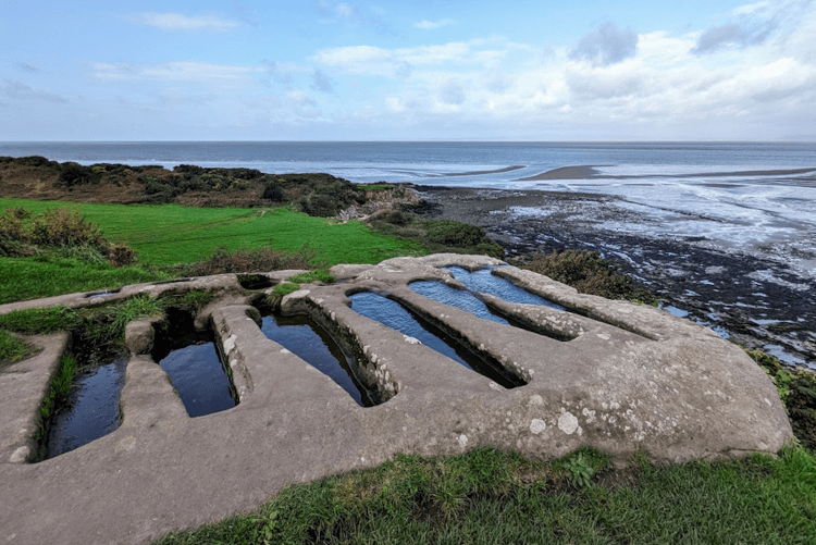 Graves cut into the rock at Heysham have filled up with rainwater and reflect the sky.