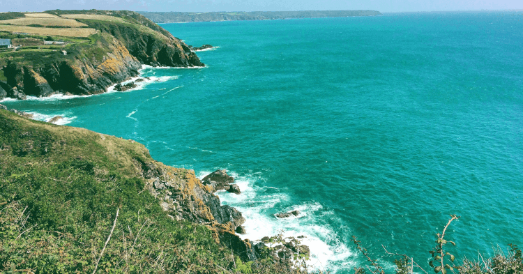 Views from the cliffs across blue ocean on the South West Coast Path.