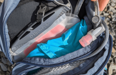 A hydration pouch nestles in its dedicated pocket at the back of a hiking backpack.