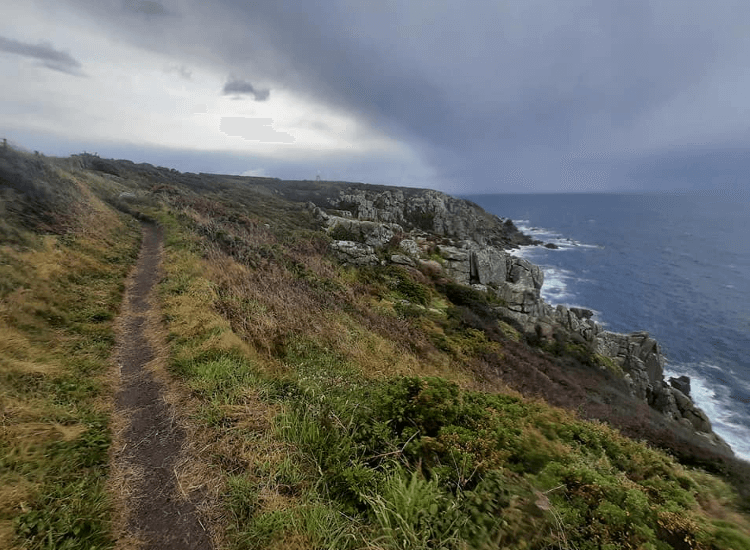 Inclement weather brings in storm clouds over a narrow path along the coast.