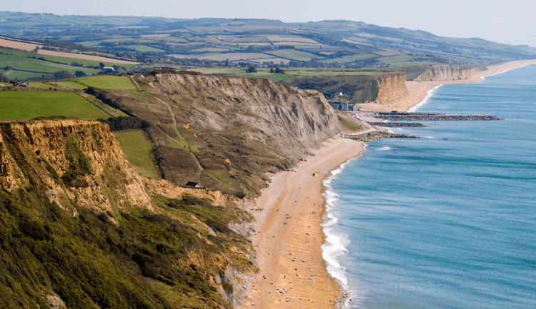 The Jurassic Coast stretches along the Atlantic coast, with orange cliffs reaching down to the sea: easily one of the 5 Top Coastal Walks in the UK