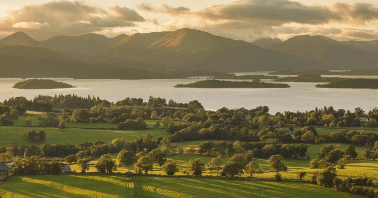Deep sunlight falls across Loch Lomond during golden hour.