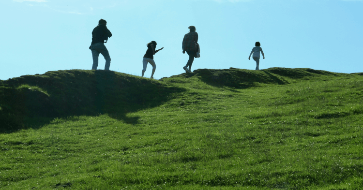 A photo of several walkers hiking along a ridge, taken at a low angle.