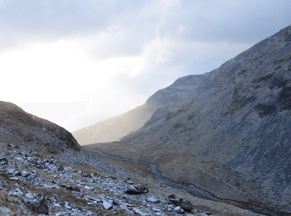 Kirkstone Pass by Mark Croston. The sun catches mist floating over Kirkstone Pass, a road between two rocky hillsides.