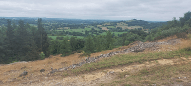 A footpath climbs into the hills, with views over trees and stone walls.