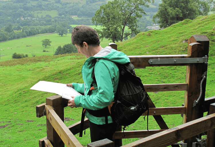 A walker checks her map at a stile on the Nidderdale Way.