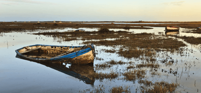 An old boat lies low in the water in the marshes along the Norfolk Coast Path.