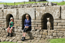 A family (and dog) sit in alcoves at a Roman fort they visited on their Hadrian's Wall Path walking holiday with Contours.