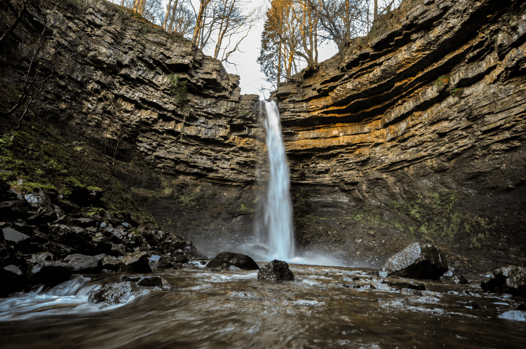 Nature walks on the Pennine Way: water tumbles over a sheer stone edge into a pool.