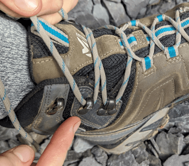 A hiker points out the penultimate hook on her boots.