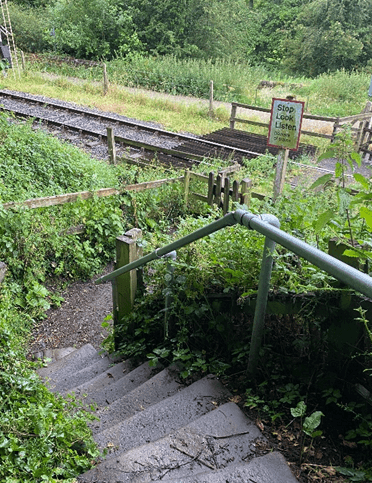 A Slow Ways path descends down steps toward a railway crossing point.