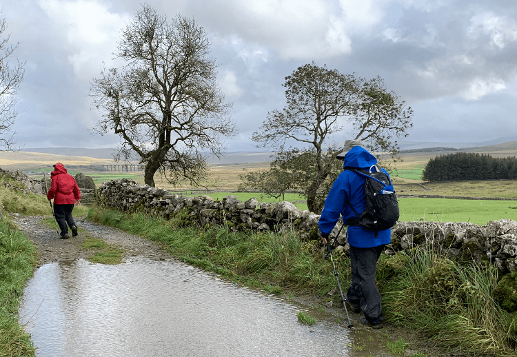 Hiking through sheeting rain in a good waterproof coat, proving it's a walking holiday kit essential.