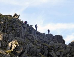Walkers take on a more challenging route toward Helvellyn, scrambling over boulders.